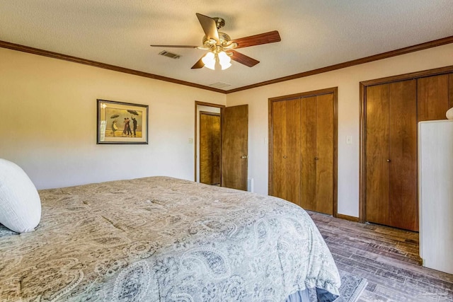 bedroom featuring a textured ceiling, dark hardwood / wood-style floors, ceiling fan, and multiple closets