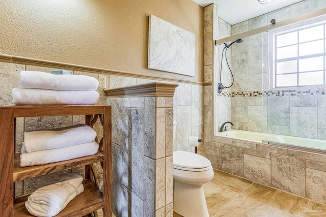 bathroom featuring bath / shower combo with glass door and toilet