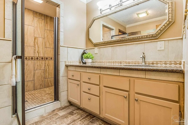 bathroom featuring vanity, crown molding, hardwood / wood-style flooring, tile walls, and a shower with shower door