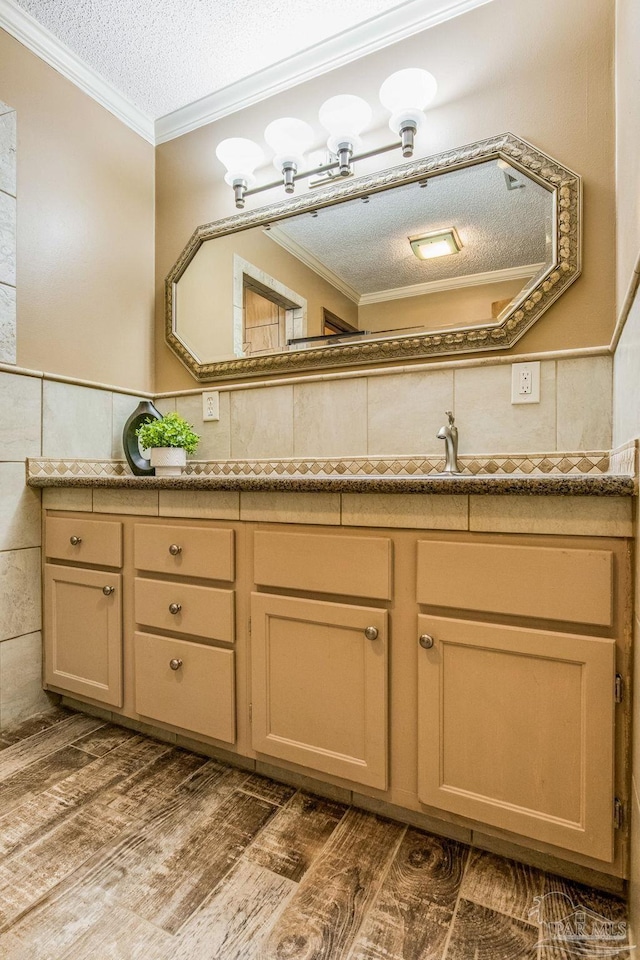 bathroom featuring vanity, wood-type flooring, a textured ceiling, and ornamental molding