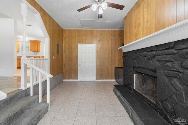 401 Ronda St, Pensacola, FL 32534 - living room with wooden walls, ceiling fan, a stone fireplace, light tile patterned floors, and a textured ceiling