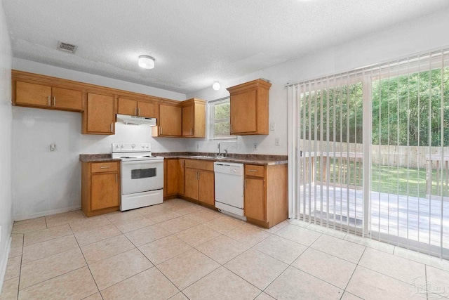 401 Ronda St, Pensacola, FL 32534 - kitchen featuring white appliances, under cabinet range hood, dark countertops, brown cabinetry, and a textured ceiling