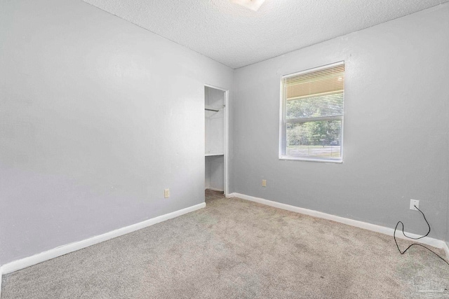 401 Ronda St, Pensacola, FL 32534 - unfurnished bedroom featuring carpet flooring, a textured ceiling, a walk in closet, and baseboards