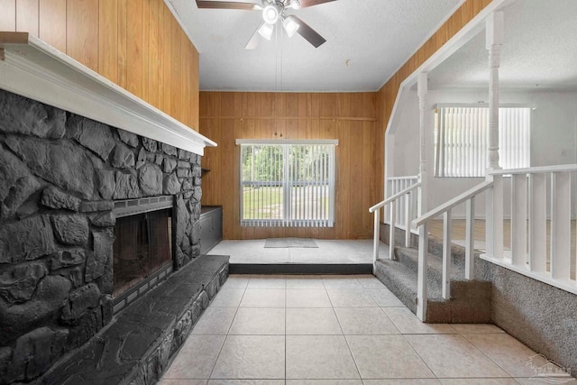 401 Ronda St, Pensacola, FL 32534 - unfurnished living room featuring ceiling fan, wooden walls, stairs, tile patterned flooring, and a fireplace