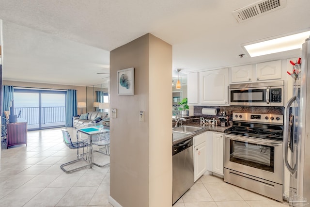 kitchen featuring sink, stainless steel appliances, tasteful backsplash, white cabinets, and light tile patterned flooring