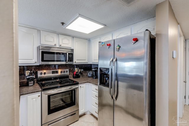 kitchen with stainless steel appliances, white cabinets, a textured ceiling, and decorative backsplash