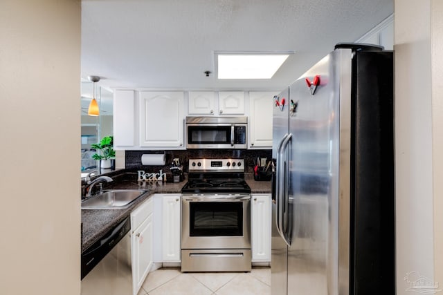 kitchen featuring sink, light tile patterned floors, appliances with stainless steel finishes, white cabinets, and decorative backsplash