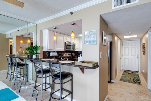 13817 Perdido Key Dr Unit 703, Pensacola, FL 32507 - kitchen featuring stainless steel appliances, a breakfast bar, white cabinets, and kitchen peninsula