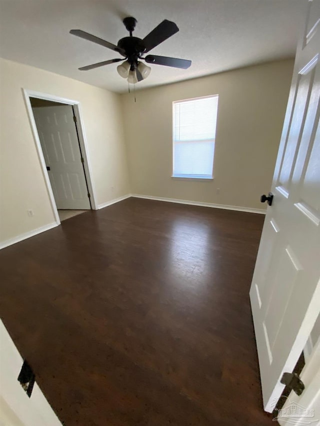 spare room with dark wood-type flooring and ceiling fan