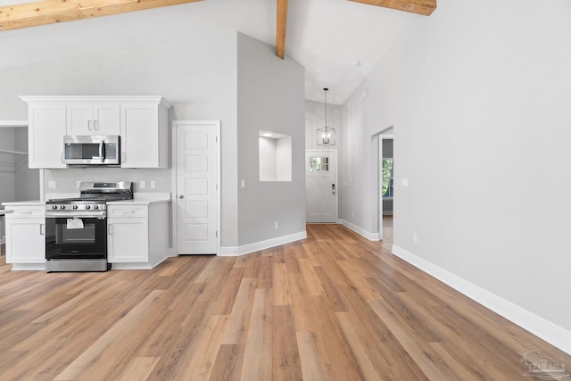 kitchen featuring light hardwood / wood-style flooring, hanging light fixtures, beam ceiling, stainless steel appliances, and white cabinets