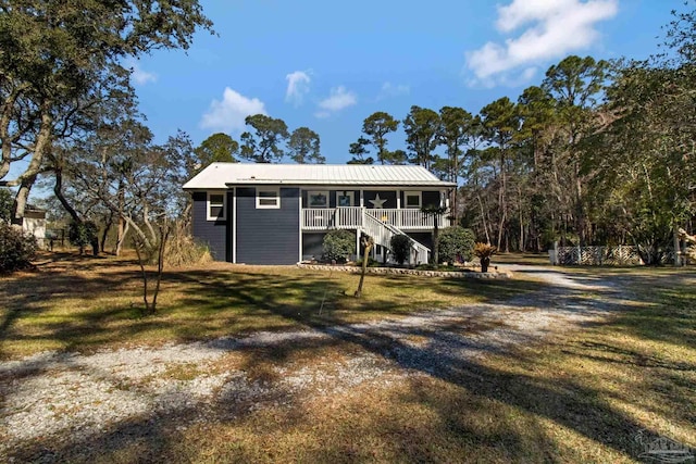 view of front of house with covered porch, metal roof, a front yard, and stairs