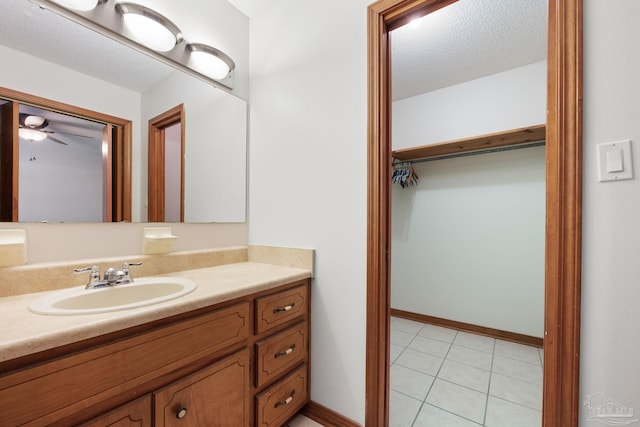bathroom with tile patterned flooring, vanity, a textured ceiling, a ceiling fan, and baseboards