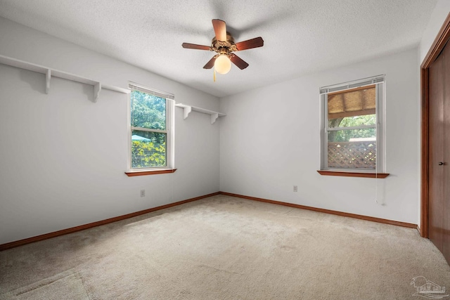 spare room featuring a textured ceiling, carpet, and ceiling fan