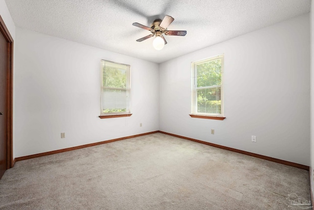 carpeted spare room with baseboards, a ceiling fan, and a textured ceiling