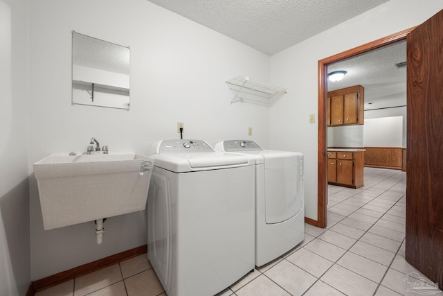 clothes washing area with washer and dryer, a textured ceiling, laundry area, and a sink