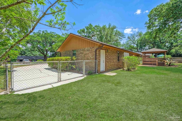 exterior space featuring fence, a gazebo, brick siding, a gate, and a lawn