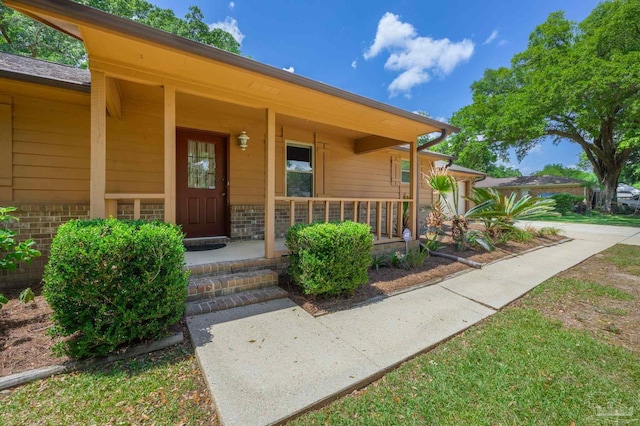 property entrance featuring a porch and brick siding
