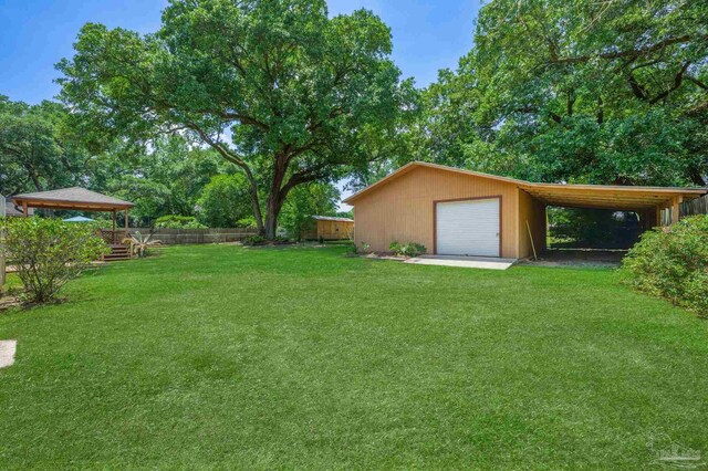 view of yard featuring fence, an outbuilding, and a detached garage