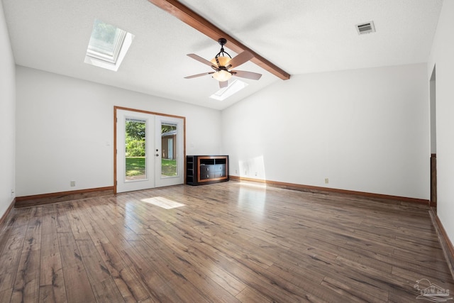 unfurnished living room featuring ceiling fan, hardwood / wood-style floors, baseboards, visible vents, and lofted ceiling with skylight