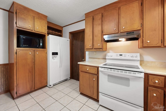 kitchen featuring light countertops, brown cabinetry, under cabinet range hood, and white appliances