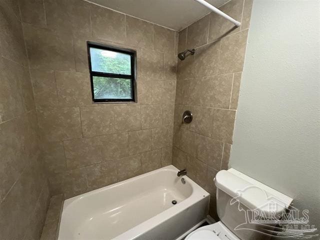 bathroom featuring tiled shower / bath combo and toilet