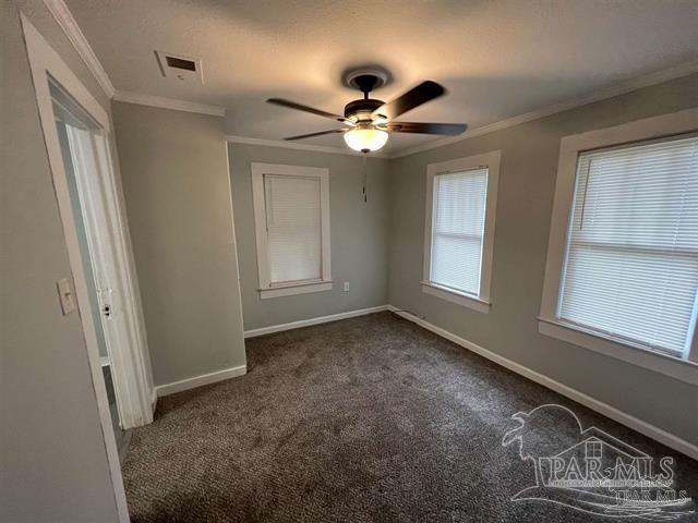 unfurnished room with crown molding, ceiling fan, and dark colored carpet