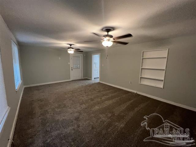 carpeted empty room featuring built in shelves, ceiling fan, and a textured ceiling