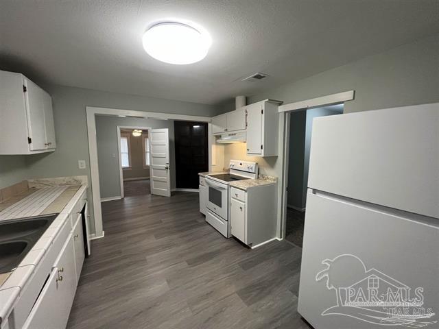 kitchen featuring white appliances, dark wood-type flooring, tile countertops, and white cabinets