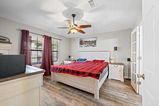 5590 Meadow Creek Pl, Gulf Breeze, FL 32563 - bedroom featuring light wood finished floors, a textured ceiling, ceiling fan, and french doors