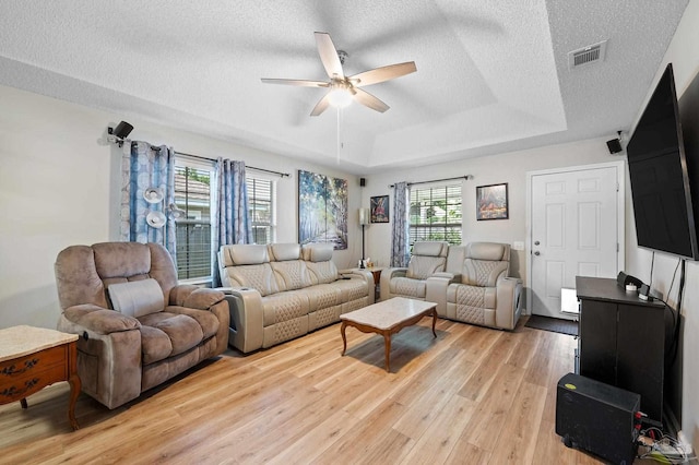 5590 Meadow Creek Pl, Gulf Breeze, FL 32563 - living room featuring light wood-style flooring, ceiling fan, a raised ceiling, healthy amount of natural light, and a textured ceiling