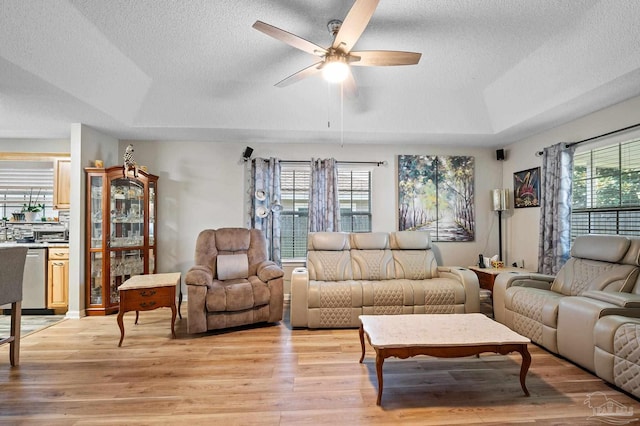 5590 Meadow Creek Pl, Gulf Breeze, FL 32563 - living area with a tray ceiling, a textured ceiling, a ceiling fan, and light wood-style flooring