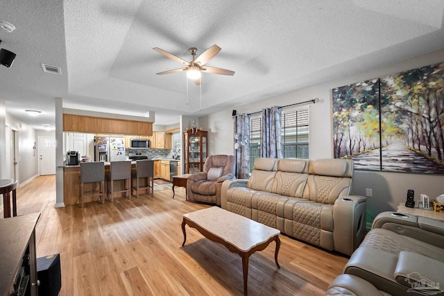 5590 Meadow Creek Pl, Gulf Breeze, FL 32563 - living area featuring a tray ceiling, ceiling fan, light wood-style flooring, and a textured ceiling