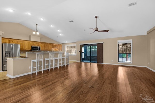 unfurnished living room with sink, ceiling fan with notable chandelier, hardwood / wood-style floors, and lofted ceiling