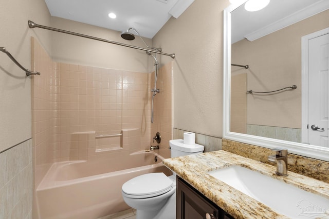 full bathroom featuring ornamental molding, vanity, tiled shower / bath, and toilet