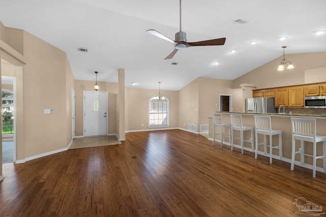 unfurnished living room featuring ceiling fan with notable chandelier, lofted ceiling, dark wood-type flooring, and sink