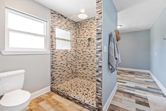 bathroom with tiled shower, hardwood / wood-style floors, and toilet