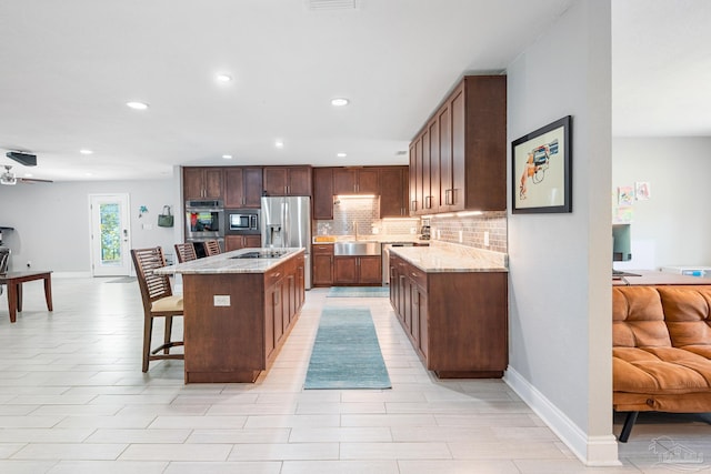 kitchen with ceiling fan, decorative backsplash, a kitchen island, a breakfast bar, and appliances with stainless steel finishes