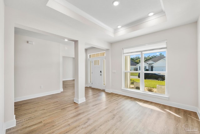 interior space with a tray ceiling and light wood-type flooring