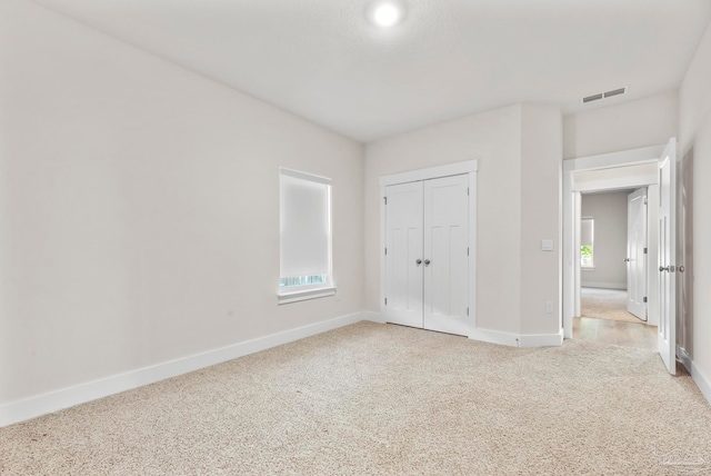 unfurnished bedroom featuring light carpet and a closet