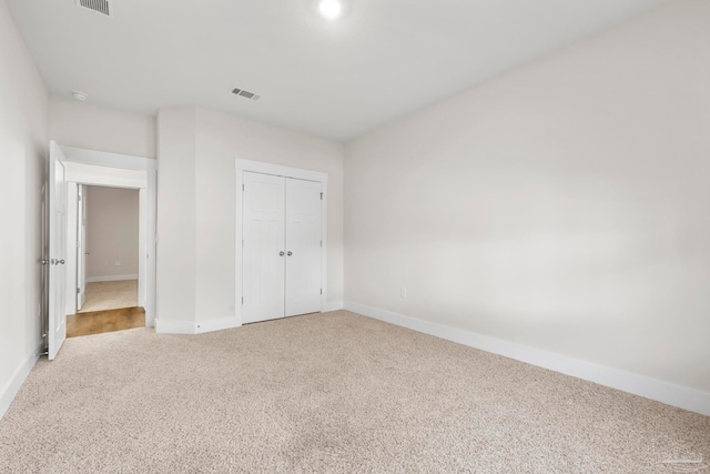 unfurnished bedroom with a closet and light colored carpet