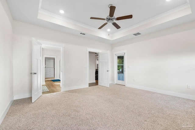 unfurnished bedroom featuring light colored carpet, a raised ceiling, and ceiling fan