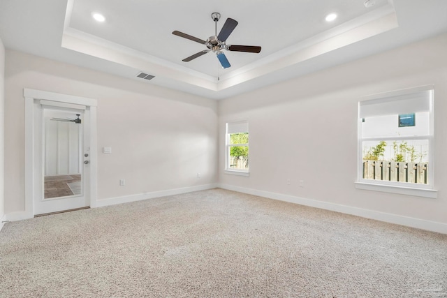 carpeted spare room featuring a tray ceiling, ceiling fan, and crown molding