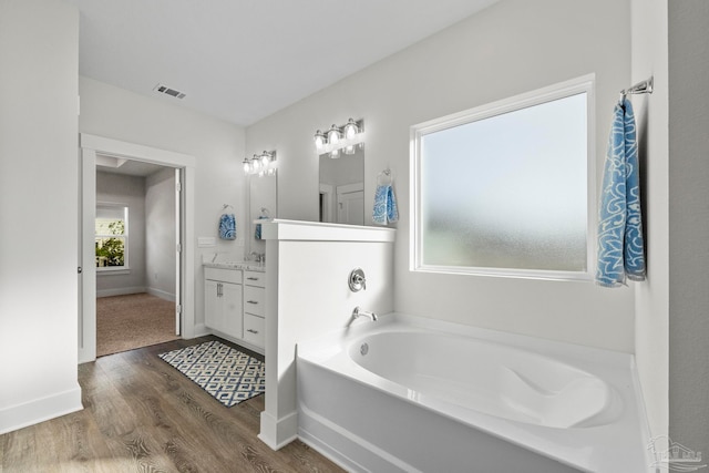 bathroom featuring hardwood / wood-style flooring, vanity, and a tub to relax in