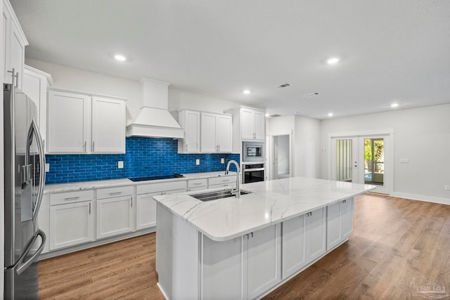 kitchen featuring white cabinetry, sink, stainless steel appliances, and a center island with sink