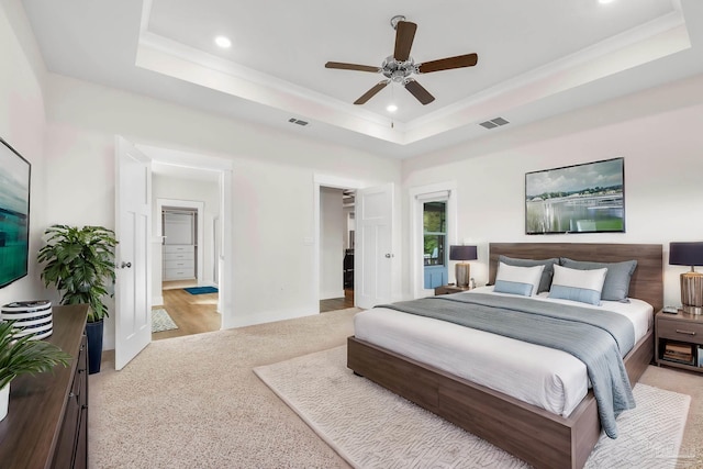 bedroom featuring ceiling fan, a raised ceiling, and light colored carpet