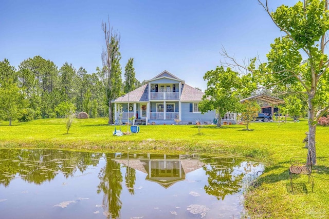 rear view of property featuring a porch, a lawn, a balcony, and a water view