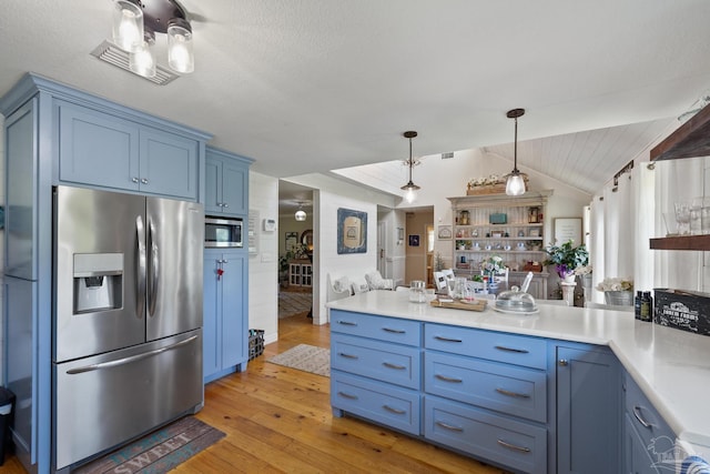 kitchen featuring appliances with stainless steel finishes, pendant lighting, blue cabinets, lofted ceiling, and light hardwood / wood-style flooring