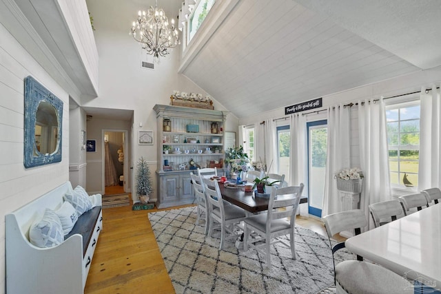 dining space featuring a chandelier, light wood-type flooring, and high vaulted ceiling