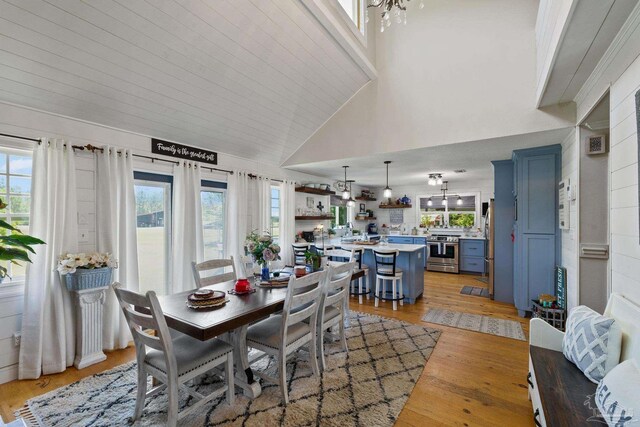 dining area featuring an inviting chandelier, light hardwood / wood-style floors, and high vaulted ceiling