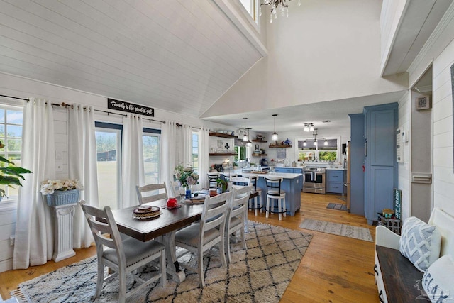 dining space with a wealth of natural light, high vaulted ceiling, and light hardwood / wood-style flooring